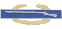 Decorative badge with a blue background and gold laurel wreath featuring a rifle.