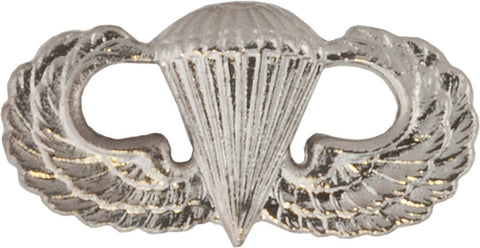 Silver metal parachutist badge insignia featuring a parachute flanked by wings, representing the Parachutist Badge.