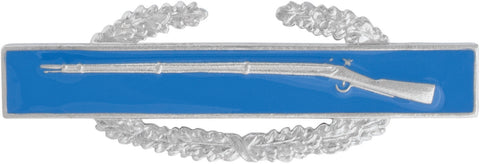 Decorative metal pin with a rifle and laurel in silver and wreath on a blue background